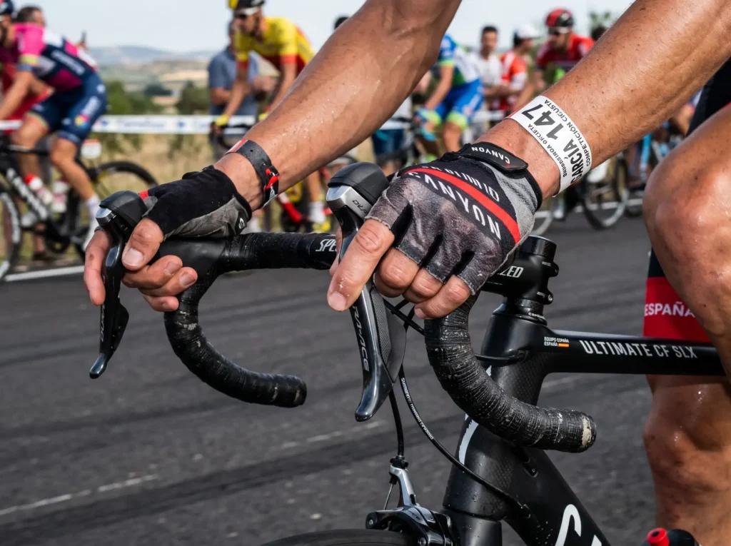 Vista cercana de las manos de un ciclista profesional sobre el manillar de una bicicleta de carretera durante una competición
